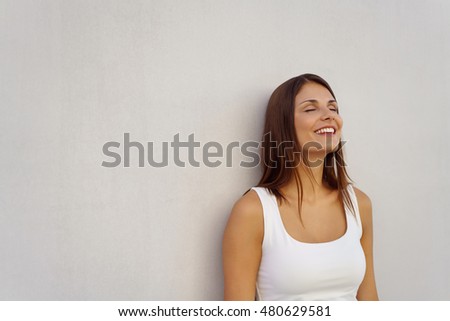 Woman with relieved expression and closed eyes leaning against blank white wall with copy space Royalty-Free Stock Photo #480629581
