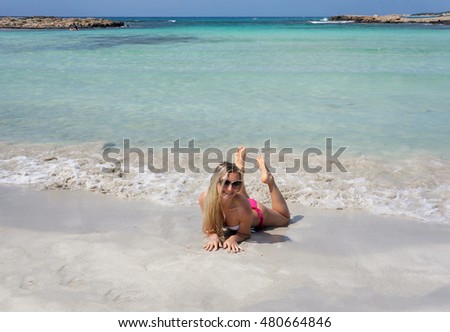 Smiling beautiful blond girl are lying on the beach in sunglasses                   
