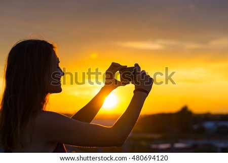Tourist hand holding smart phone and taking photo of beautiful beach sunset