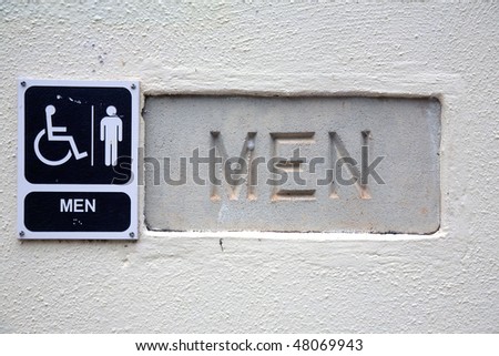 cement men's restroom sign with a handicap placard also in Braille for the blind to read
