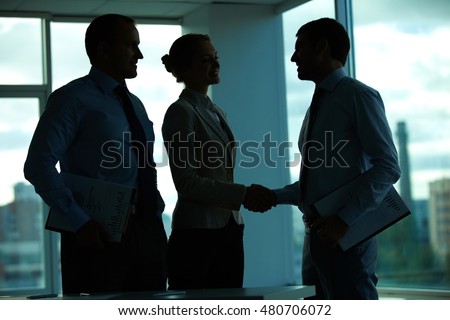 Three business people greeting in office in the dark