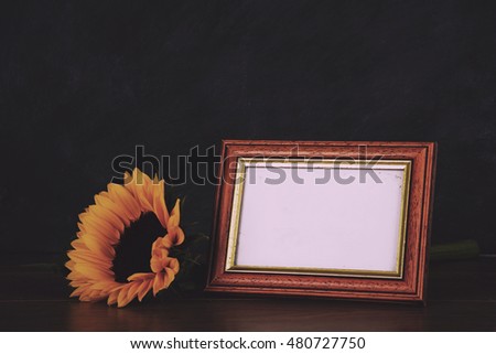 Old picture frame and sunflower against a dirty blackboard background Vintage Retro Filter.