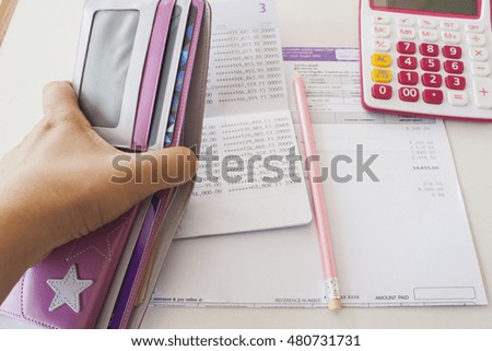 document monthly expense of credit card hand holding purse money and check account
