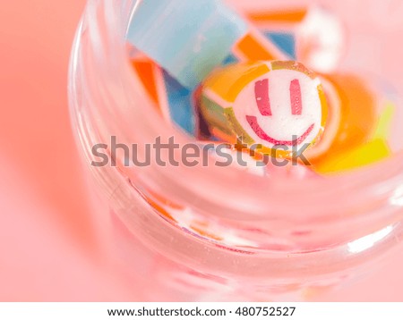 Vintage tone. Closeup at smiley face and colorful candy canes in glass jar.