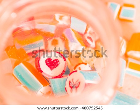 Vintage tone. Closeup at red heart and colorful candy canes in glass jar.