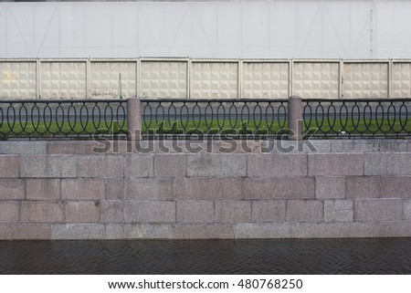 Stone embankment with railings and concrete fence