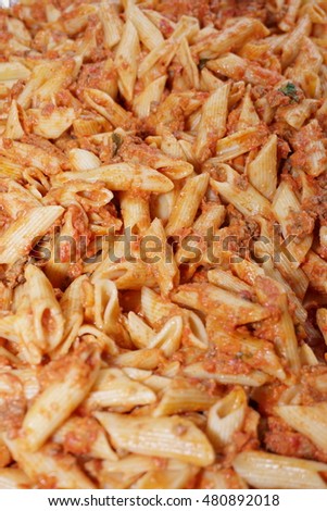 Tray of penne ala vodka macaroni pasta dish serving people at a party. background image.