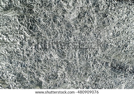 sheet of silver leaf background with shiny crumpled uneven surface
