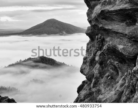 Spring misty landscape. Early morning ina beautiful mountains of Bohemian-Saxony Switzerland. Peaks of hills increased from heavy creamy fog. 