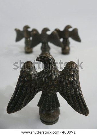 Single eagle sculpture facing left in foreground and three facing right blurred in background