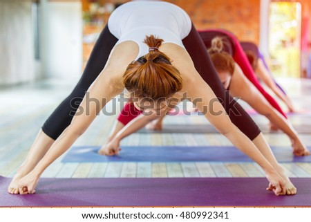 Fitness asian female group doing warm up yoga pose in row at the yoga class. selective focus