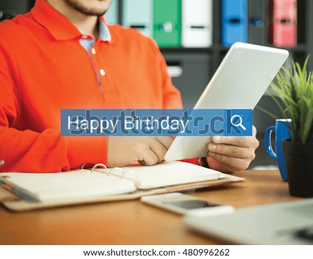 Young man working in an office with tablet pc and searching HAPPY BIRTHDAY word on internet