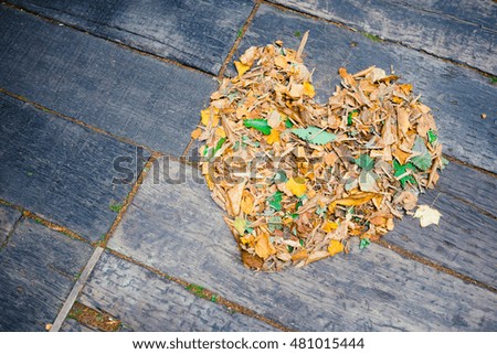 Heart shape from dry leaf texture on wooden floor background.Selective center focus.