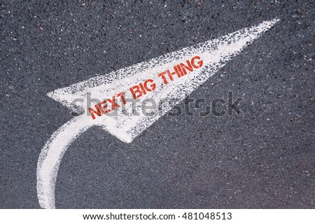 Directional white painted arrow with words NEXT BIG THING over road surface, concept image