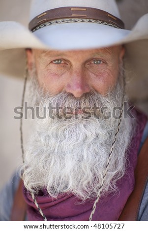 A cowboy with a white beard looking at camera