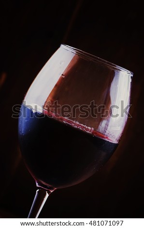 Chilled dry red wine in the glass. Dark vintage wood background. Low key, selective focus.
