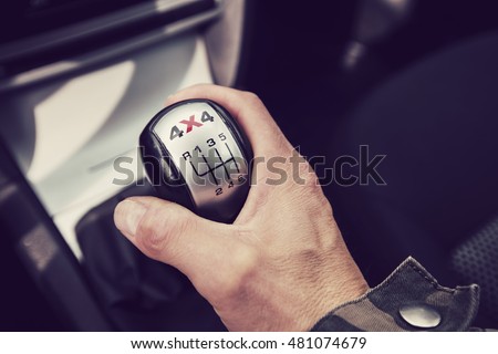 Close-up photo of four-wheel drive vehicle shifter in Finland. The photograph is also a man's hand changing gear.. Image includes a vintage effect. Royalty-Free Stock Photo #481074679