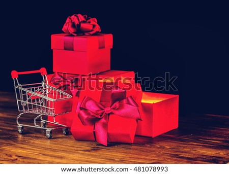 sale concert, presents, holiday greeting card with festive opened boxes with bow and shopping cart on wooden background, close up