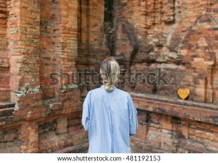 Young woman wearing traditional dress, is in ancient temple of Thailand