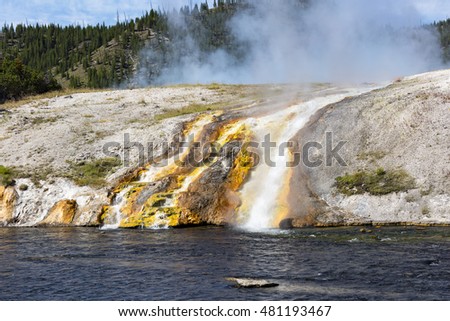 Colorful landscapes of geothermal activity of Midway Geyser Basin, Yellowstone National Park, Wyoming. Runoff flows into the Firehole River. The bright colors of the river shore.