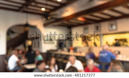 Abstract blurred French restaurant interior in French Quarter of New Orleans, Louisiana, US. People enjoying cafe, Creole cuisine, Cajun food. New Orleans deeply tied to French food culture. Panorama.