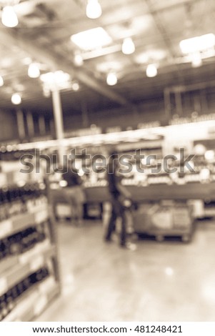 Blurred image aisle of bottles in wine section of modern distribution warehouse with employee stocks wine. Inventory, logistic, business, wholesale, export concept. Beverage alcohol background.