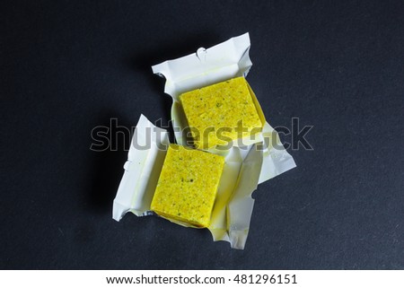 Dehydrated bouillon stock cube salty meat and vegetables aromatic yellow spice, ingredient single whole condiment portion wrapped, open in paper pack