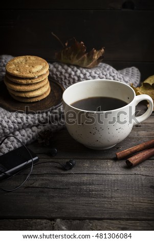 Cup of coffee/tea, cookies, fallen leaves and scarf on wooden table. Style rustic. Fall concept.