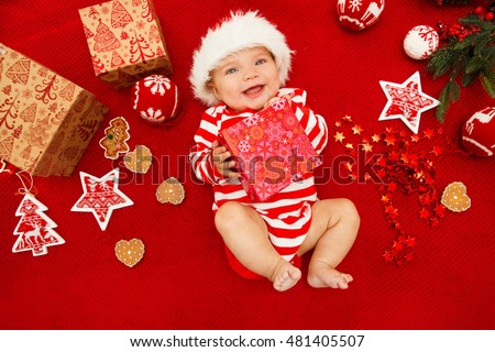 Baby first christmas. Beautiful little baby celebrates Christmas. New Year's holidays. Baby with santa hat with gift. Santa baby.