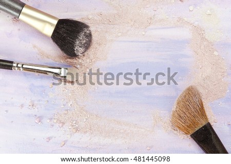Makeup brushes on a light purple background, with traces of powder and blush on it; a horizontal template for a makeup artist's business card or flyer design; with plenty of copyspace