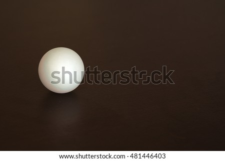 White ping-pong ball on a black desk, reflected. Royalty-Free Stock Photo #481446403