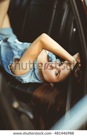 Girl lying on leather seat of car. tinted photo