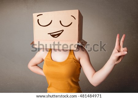 Young woman standing and gesturing with a cardboard box on her head with smiley face