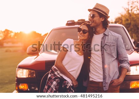 Thinking about new place to go. Beautiful young smiling couple looking thoughtful while bonding to each other and leaning at their pick-up truck  Royalty-Free Stock Photo #481495216
