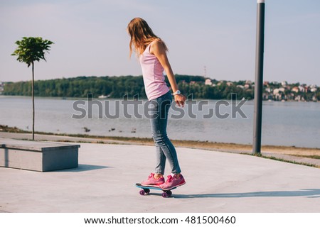 Girl riding a skateboard in the park overlooking the beach