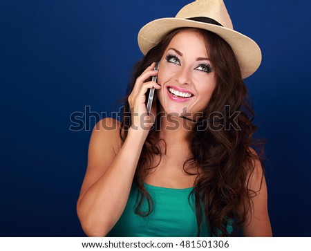 Beautiful makeup woman talking on mobile phone in summer hat on bright blue background. Curly hair style