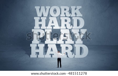 A confident salesman in suit standing in front of illustrated block letters saying work hard play hard concept
