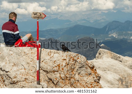 Climber resting on top Pic Boe, sign WC ALPINISTO, Dolomites, Italy
