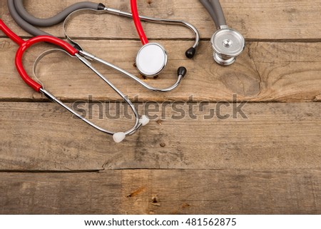 Grey and red stethoscopes on wooden desk