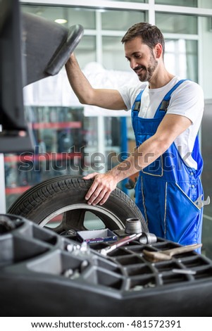 mechanic repairman installing automobile car wheel on tyre 