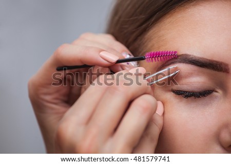 Master makeup corrects, and gives shape to pull out with forceps previously painted with henna eyebrows in a beauty salon. Professional care for face.