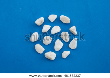 Circle of white rounded pebble stones on a blue background