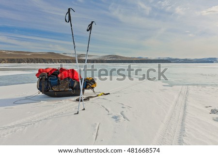 Ice sleigh and ski poles standing in the snow on the ice of Lake Baikal