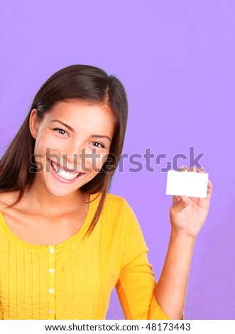 Business card woman showing friendly smile. Beautiful cute mixed race caucasian / chinese young woman model presenting a blank business card on a purple background.