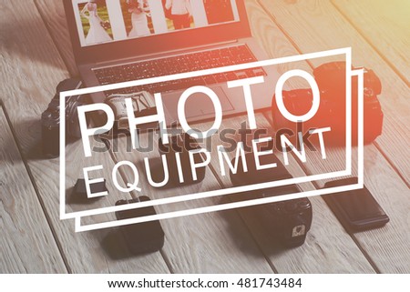 Phototechnique and laptop with money closeup. Accessories for photographing, cell phone and laptop with bundle of money on it on wooden background