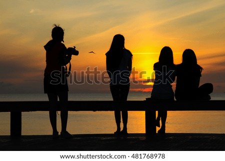 Silhouette of girl group in the morning at the beach waiting for the sunrise.