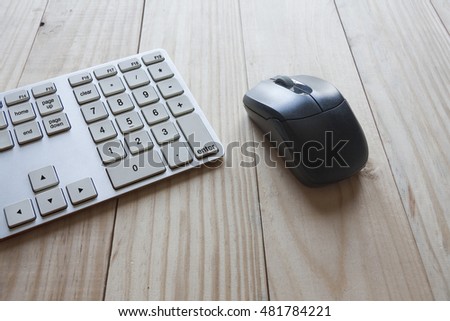 keyboard and wireless mouse on top of wooden desk. Royalty-Free Stock Photo #481784221