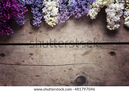 Border from aromatic lilac flowers on vintage wooden planks. Selective focus. Place for text. Floral still life. Toned image.