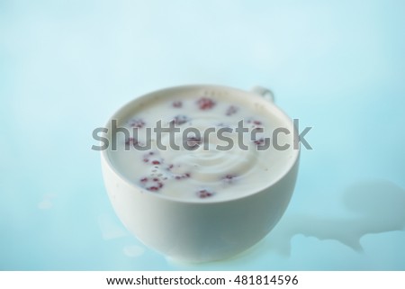 Ripples into a cup of milk with raspberries.