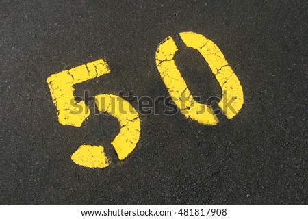 Number fifty 50  in yellow on tarmac of a parking lot. Abstract background and texture